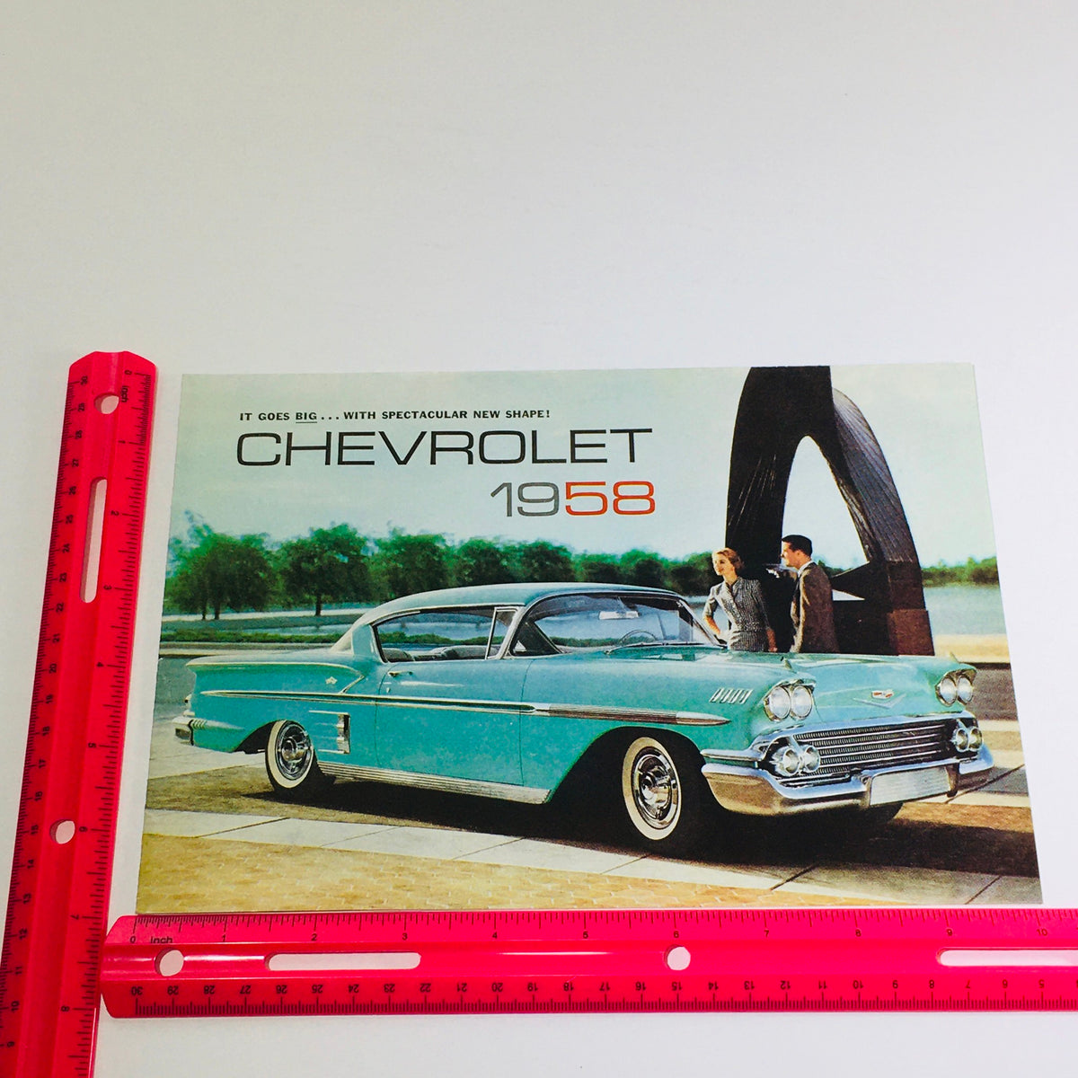 Photograph of the 1958 Chevrolet Bel Air Corvette Dealership Car Auto Brochure Catalog featuring a turquoise Chevrolet car with a ruler for size reference, capturing its vintage appeal.