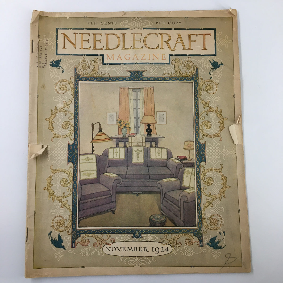 Cover of VTG Needlecraft Magazine November 1924 featuring a cozy living room scene with plush furniture.