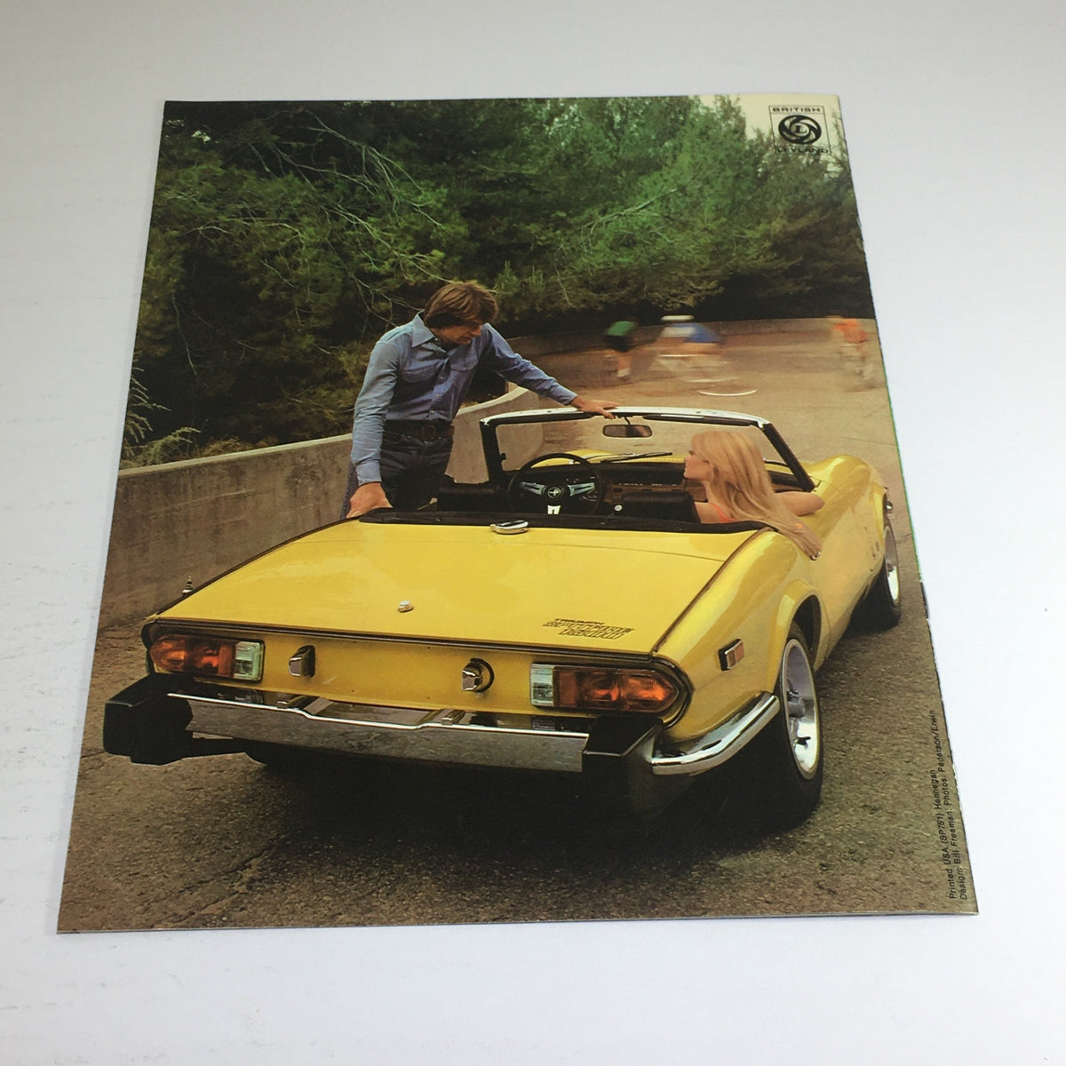 Back view of a yellow Spitfire model with a man and a woman, featured in the 1975 Spitfire Triumph Dealership Specification Car Auto Brochure Catalog.