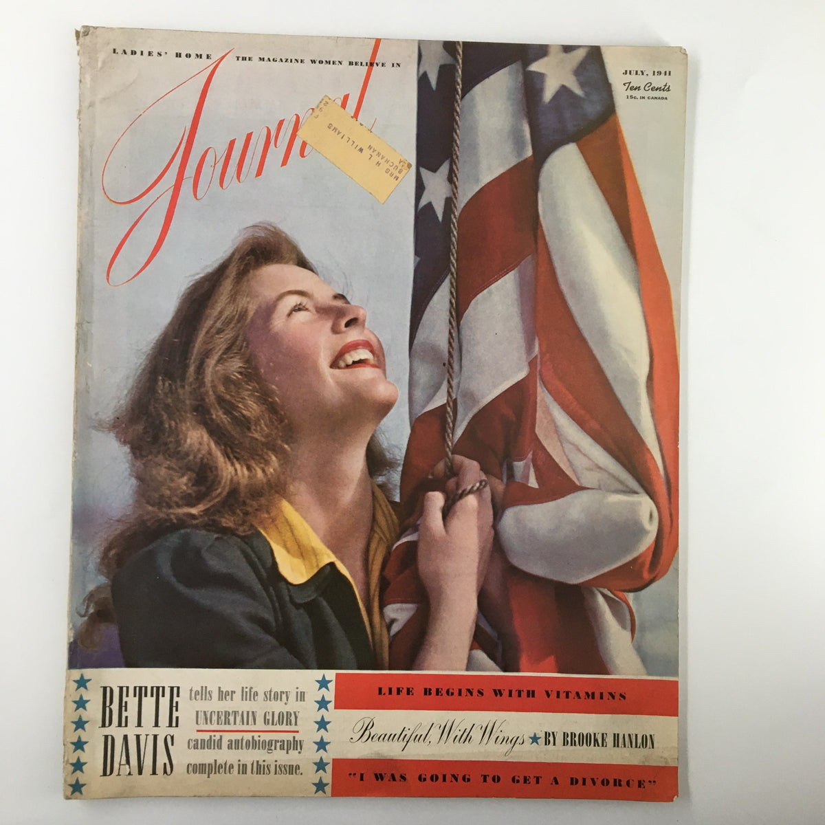 Cover of Ladies' Home Journal Magazine, July 1941, featuring a smiling woman holding an American flag; highlights the Bette Davis story 'In Uncertain Glory'.