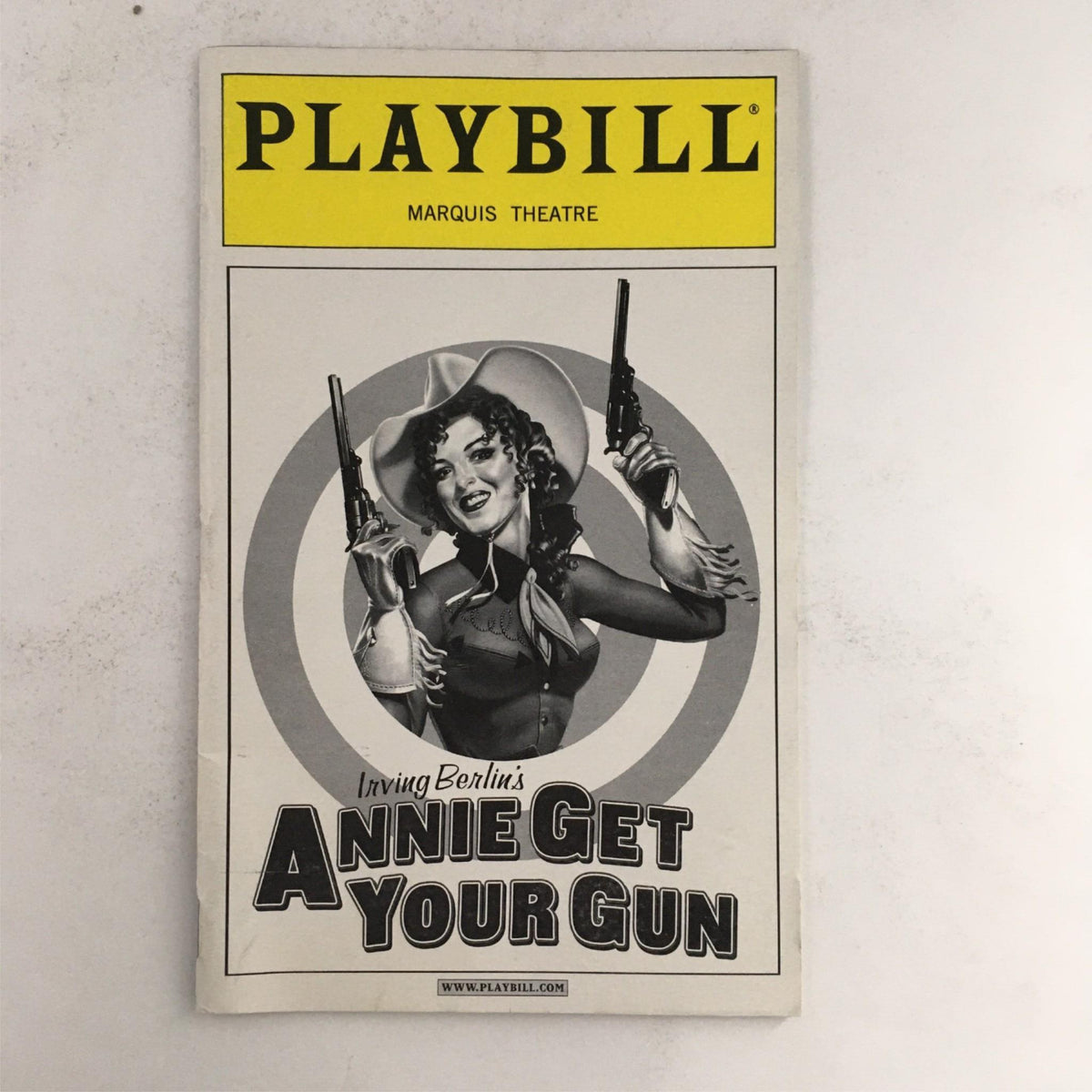 2000 Playbill for 'Annie Get Your Gun' featuring a vintage black and white image of the lead character holding guns, showcasing the artistic design and iconic elements from the production at the Marquis Theatre.