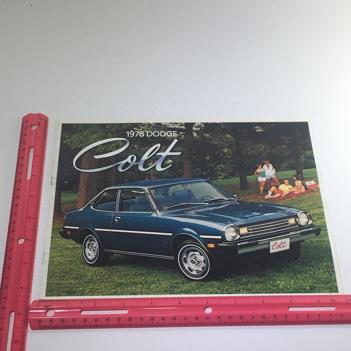 1978 Dodge Cold Custom Coupe M/M Dealership Car Auto Brochure cover featuring a blue Dodge Colt parked on grass with people enjoying a picnic in the background.