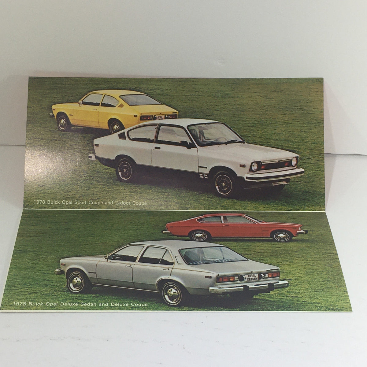 Interior of the 1978 Buick Opel Sport Coupe Deluxe Sedan brochure showcasing images of the coupe in three different colors: white, yellow, and red on a grass background.