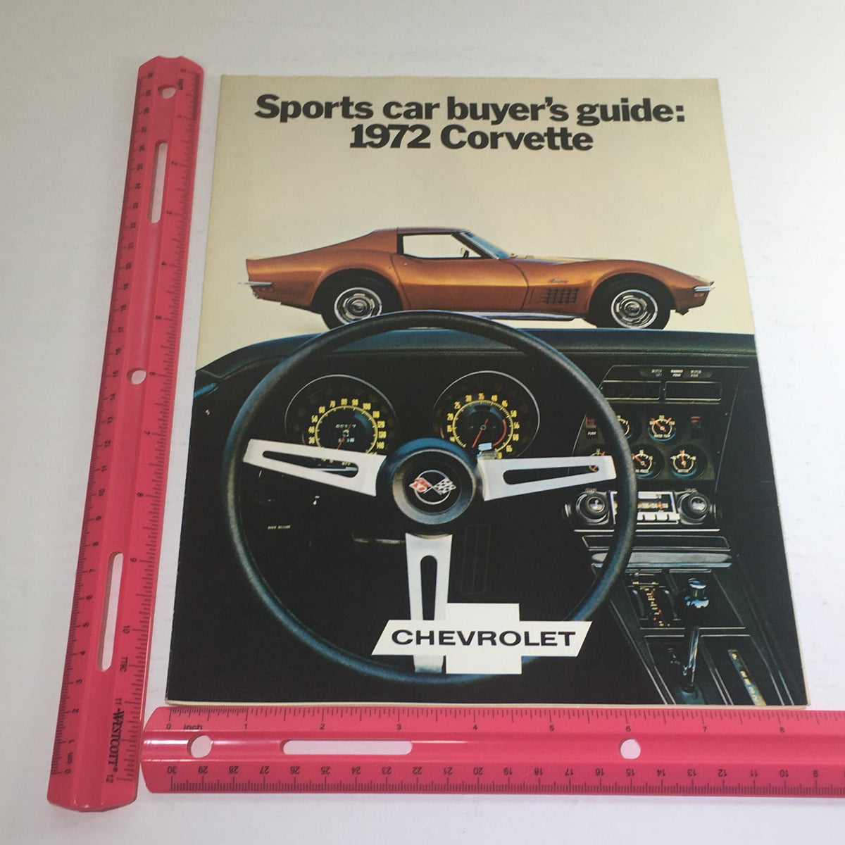 Side view of the 1972 Chevrolet Corvette Stingray brochure with a ruler for scale, displaying the iconic car and detailed dashboard.