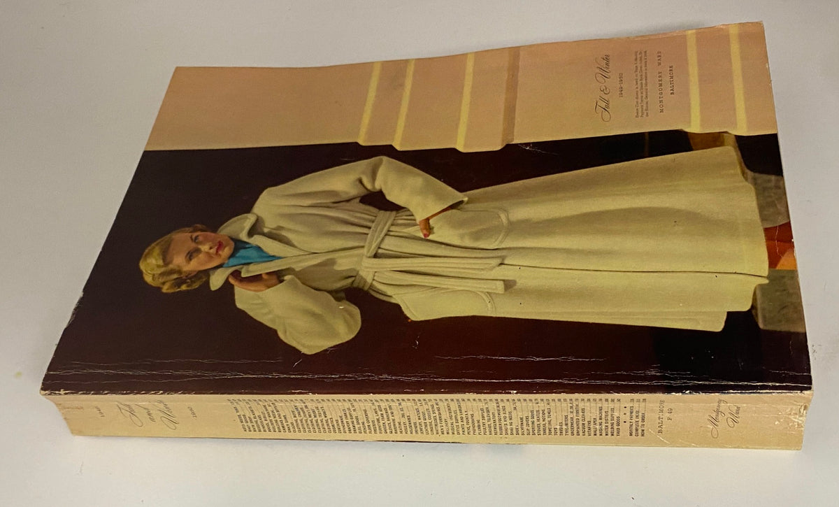 Side view of the 1949-1950 Montgomery Ward Baltimore Fall and Winter Catalog displaying its cover and spine, featuring a model in a white coat which reflects the design aesthetics of the late 1940s.