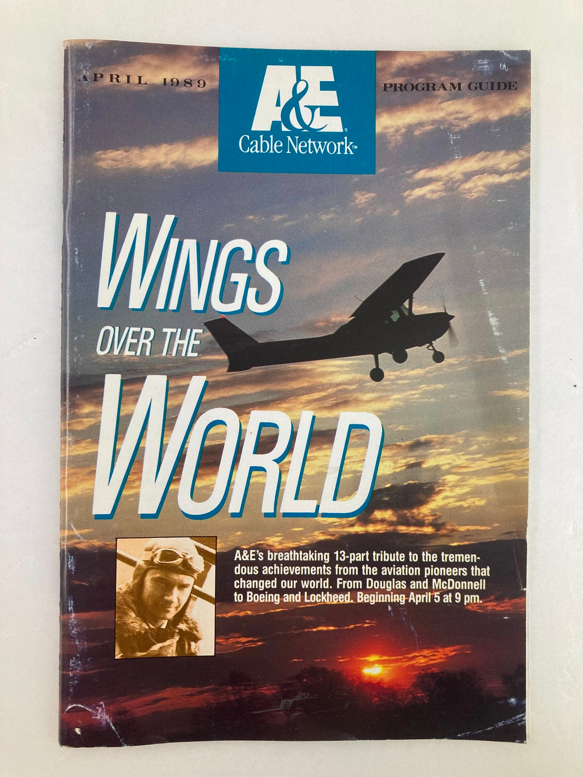 VTG A&E Cable Network Program Guide April 1989 'Wings Over The World' featuring an aircraft silhouette against a dramatic sunset, showcasing vintage television history.