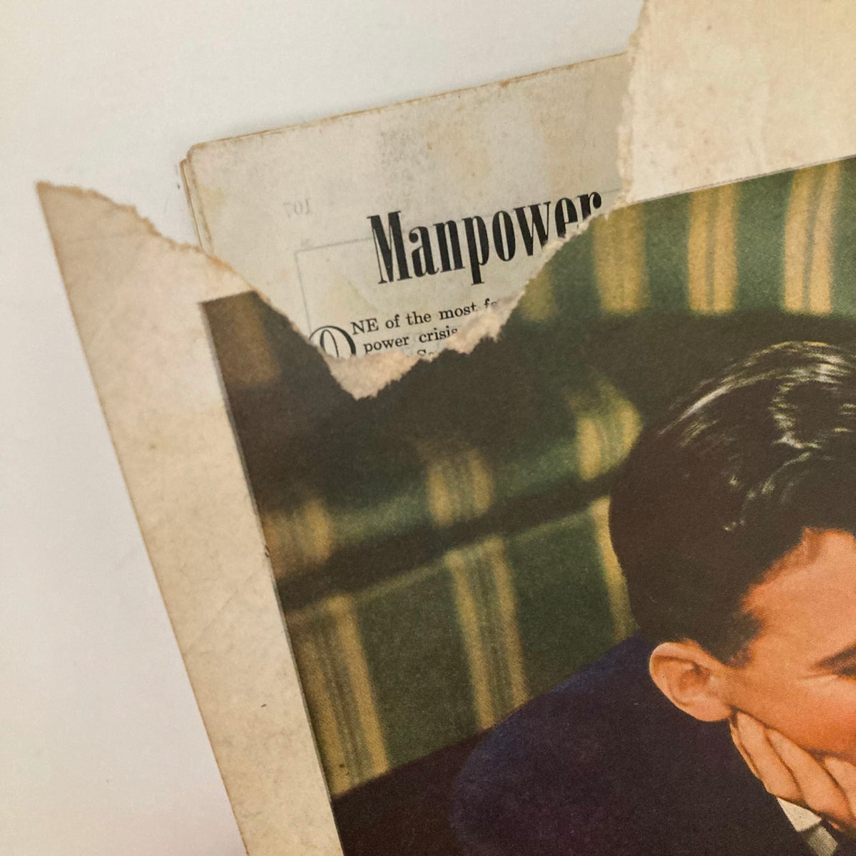 Close-up of the damaged edge of a page from the Saturday Evening Post Magazine February 10 1945, displaying a glimpse of the content about manpower.