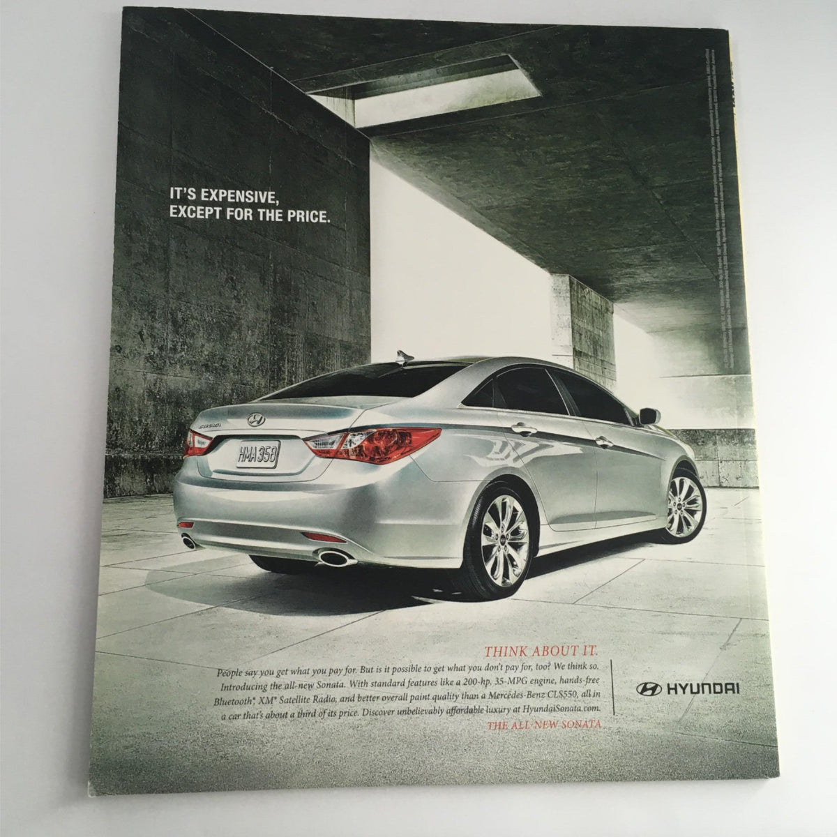 Advertisement for Hyundai showcasing a sleek silver car with modern design, including a tagline about affordability versus luxury.