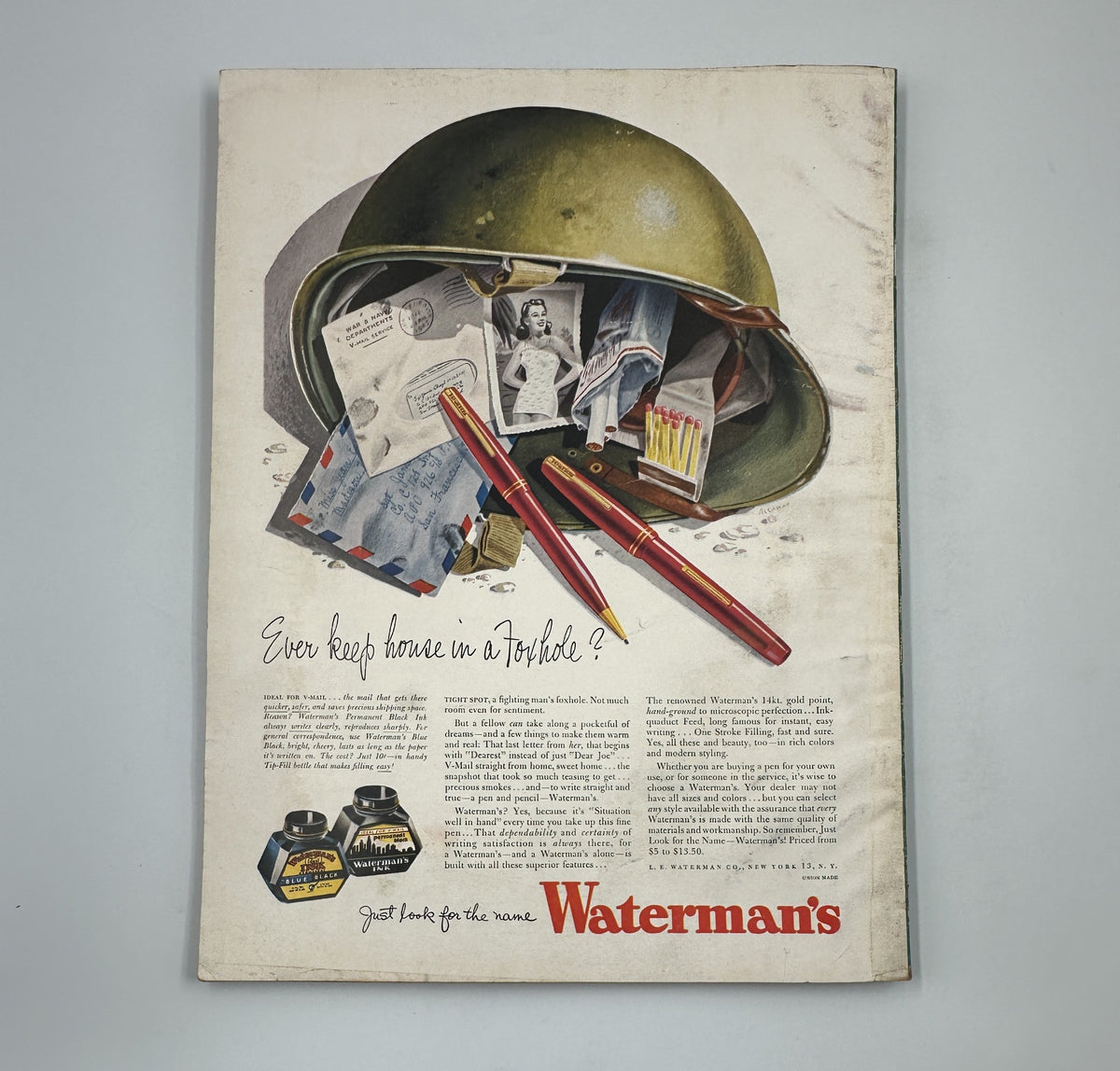A historical advertisement from Esquire Magazine June 1945 showcasing a Waterman's ink pen inside a military helmet. The ad emphasizes the tagline 'Ever keep house in a helmet?' surrounded by personal letters and documents. This visual represents a unique blend of wartime and everyday life elements.