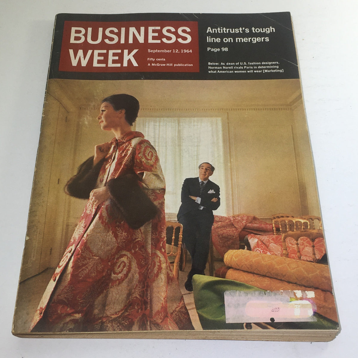 Cover of Business Week Magazine from September 12, 1964, featuring a model dressed in a luxurious Norman Norell design, showcasing the elegance of U.S. fashion in a vintage setting.