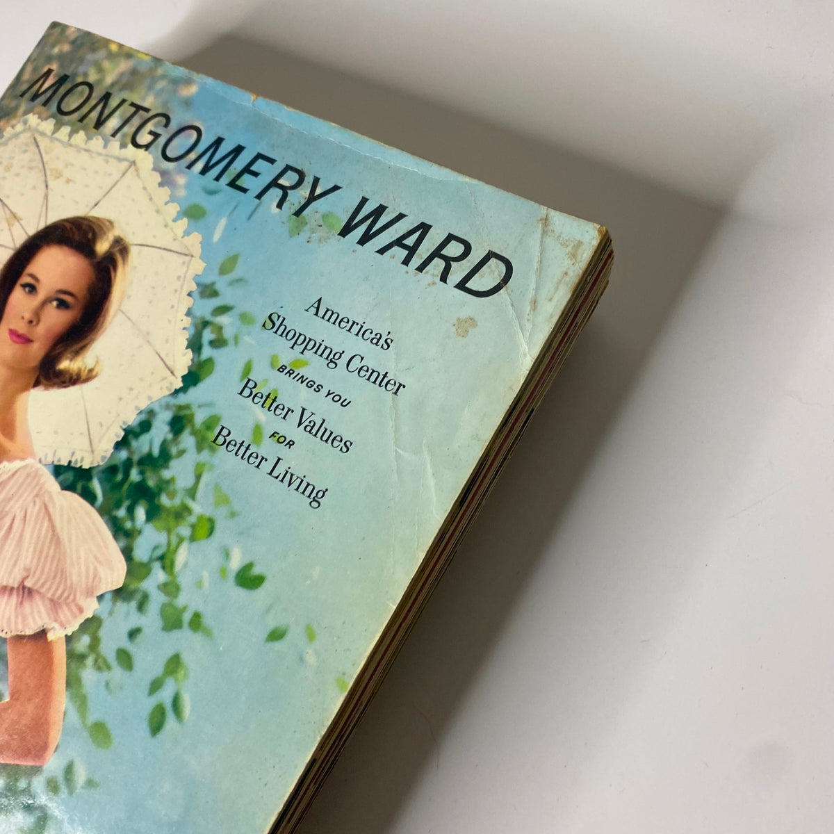 Close-up of the 1961 Montgomery Ward Spring and Summer Catalog showing the vintage cover details and woman in a pink dress.