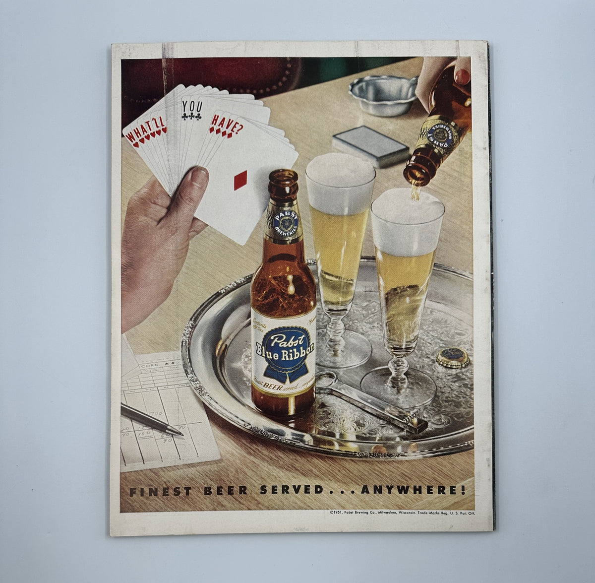 Advertisement from Esquire Magazine September 1951 for Pabst Blue Ribbon beer, depicting a hand pouring beer into glasses with playing cards on a table. This engaging visual emphasizes the magazine's emphasis on leisure and social gatherings.