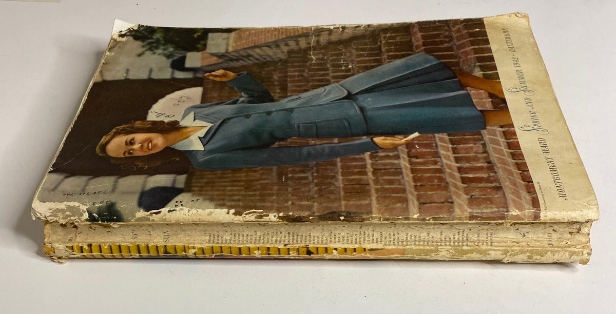 Side view of the 1942 Montgomery Ward Spring and Summer Catalog showing damage to the edges and the same woman in blue suit from the cover.