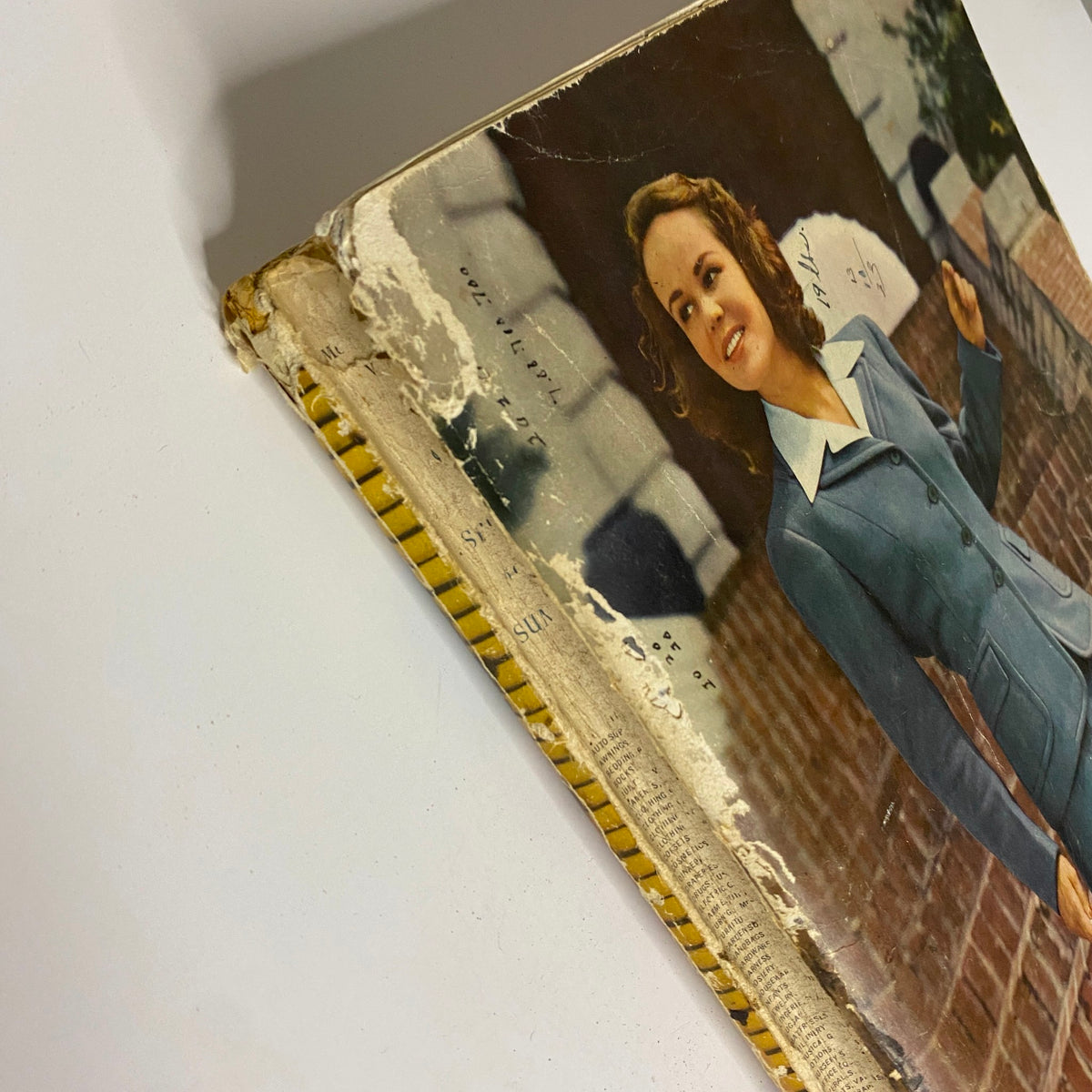 Top view of the 1942 Montgomery Ward Spring and Summer Catalog, capturing the woman's smiling face in a blue suit and marked edges.