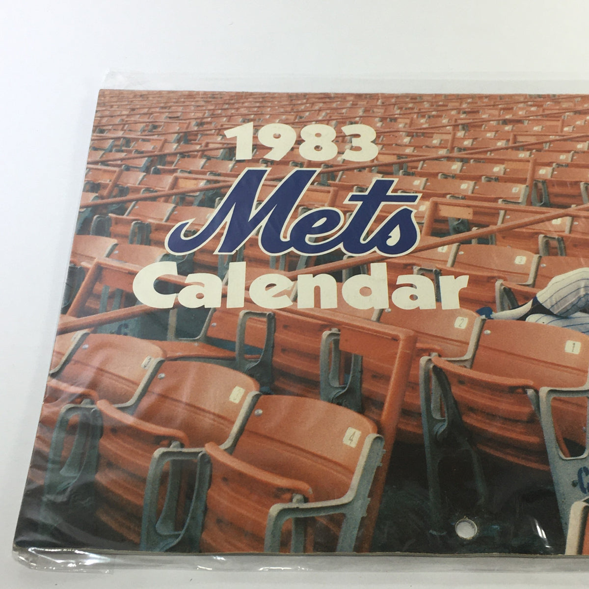 Vintage 1983 New York Mets Calendar showcasing the iconic logo and artwork, displayed against a background of empty stadium seats, ideal for baseball enthusiasts.