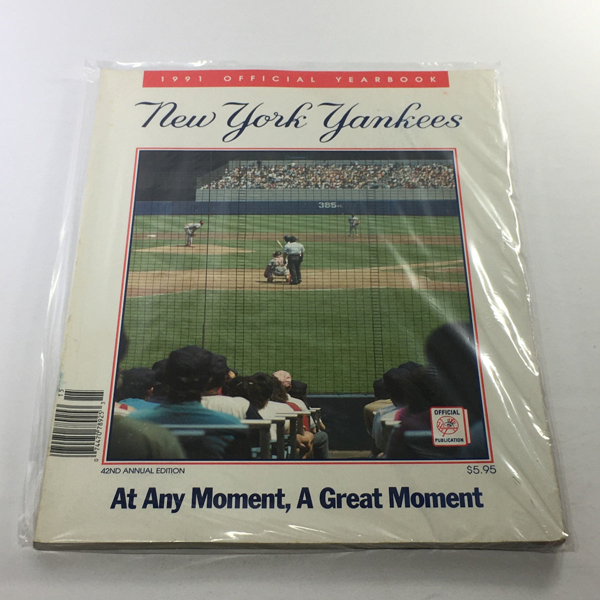 1991 New York Yankees Official Yearbook and 42nd Annual Edition showcasing a baseball game scene from the bleachers, with players on the field and fans watching the game. A collectible vintage magazine in plastic protective covering.