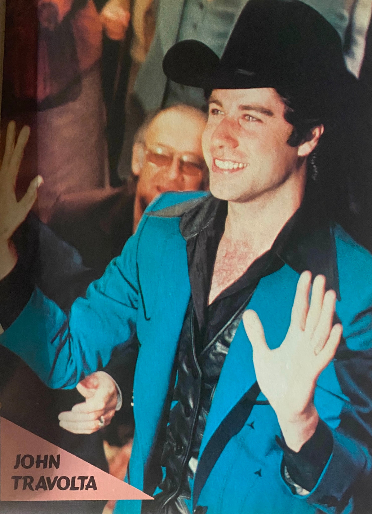 John Travolta smiling and waving in a striking blue outfit, captured in Tiger Beat Magazine October 1980, representing the iconic fashion and pop culture of the era.