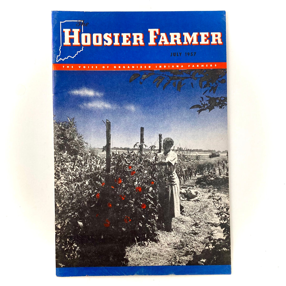 Cover of VTG The Hoosier Farmer Magazine from July 1957, featuring a woman tending to tomato plants with a scenic agricultural background.