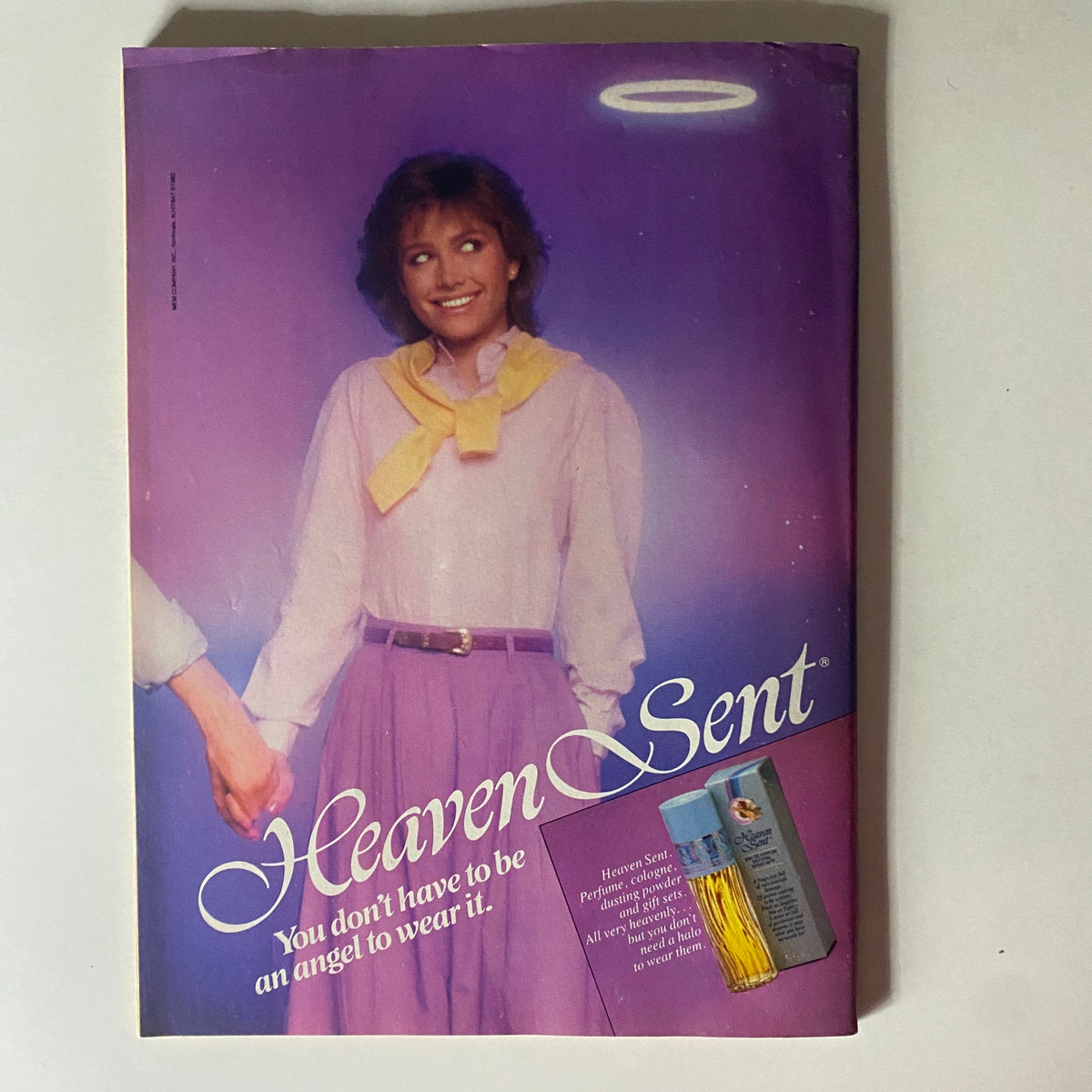 16 Magazine November 1982 - Vintage advertisement for Heaven Sent perfume featuring a stylish woman smiling, wearing pastel colors and holding hands.