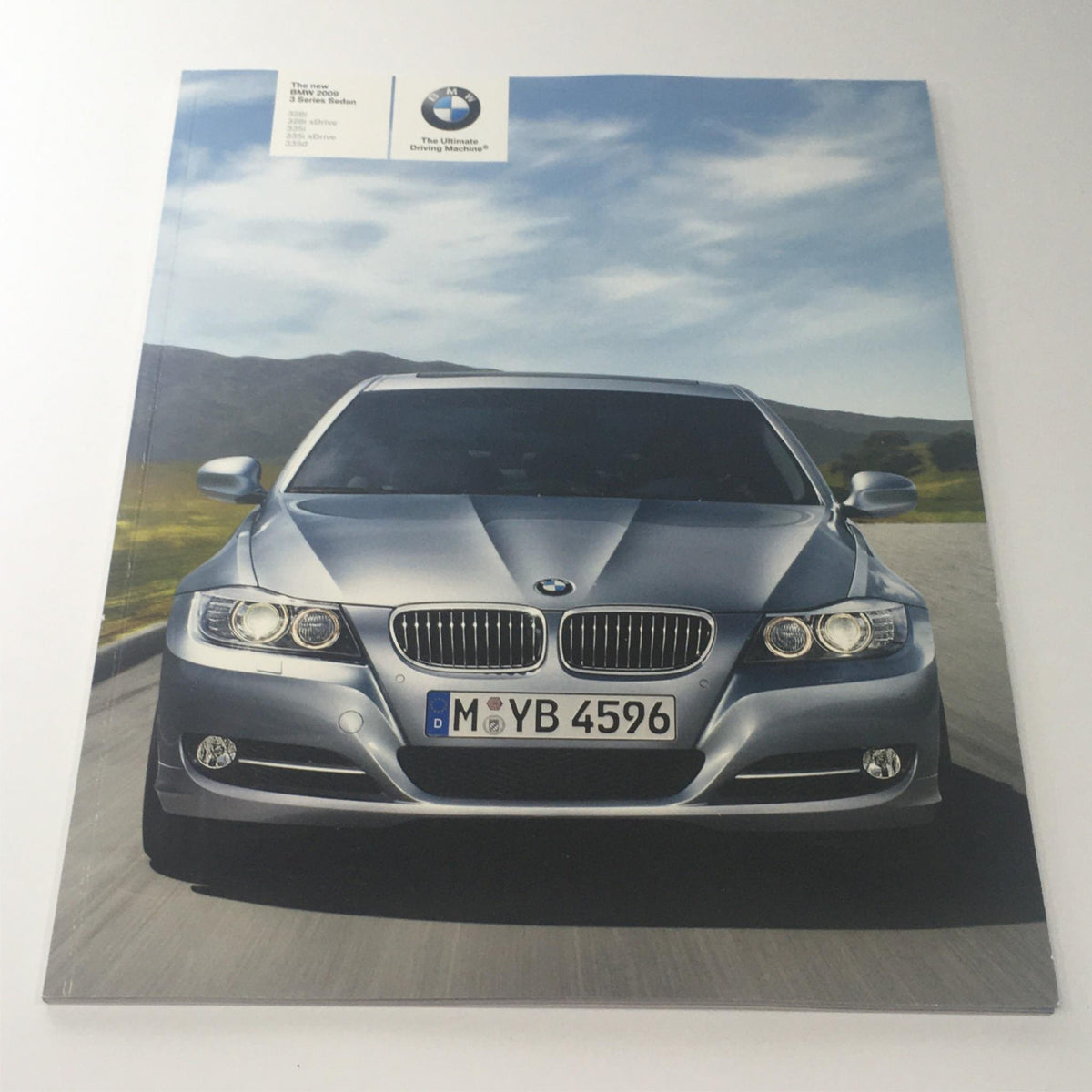 2009 BMW 3 Series Sedan brochure cover featuring a silver BMW 3 Series on a scenic road.