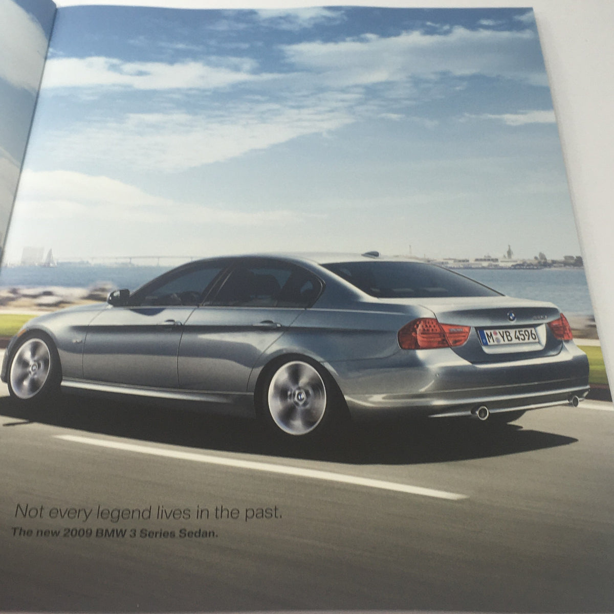 2009 BMW 3 Series Sedan brochure interior page with a silver BMW 3 Series parked against a backdrop of a cityscape.