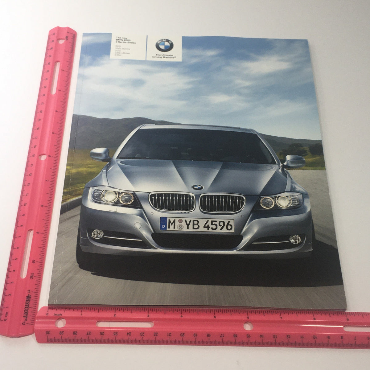 2009 BMW 3 Series Sedan brochure cover being measured with a ruler, showing size 11.10" x 9".