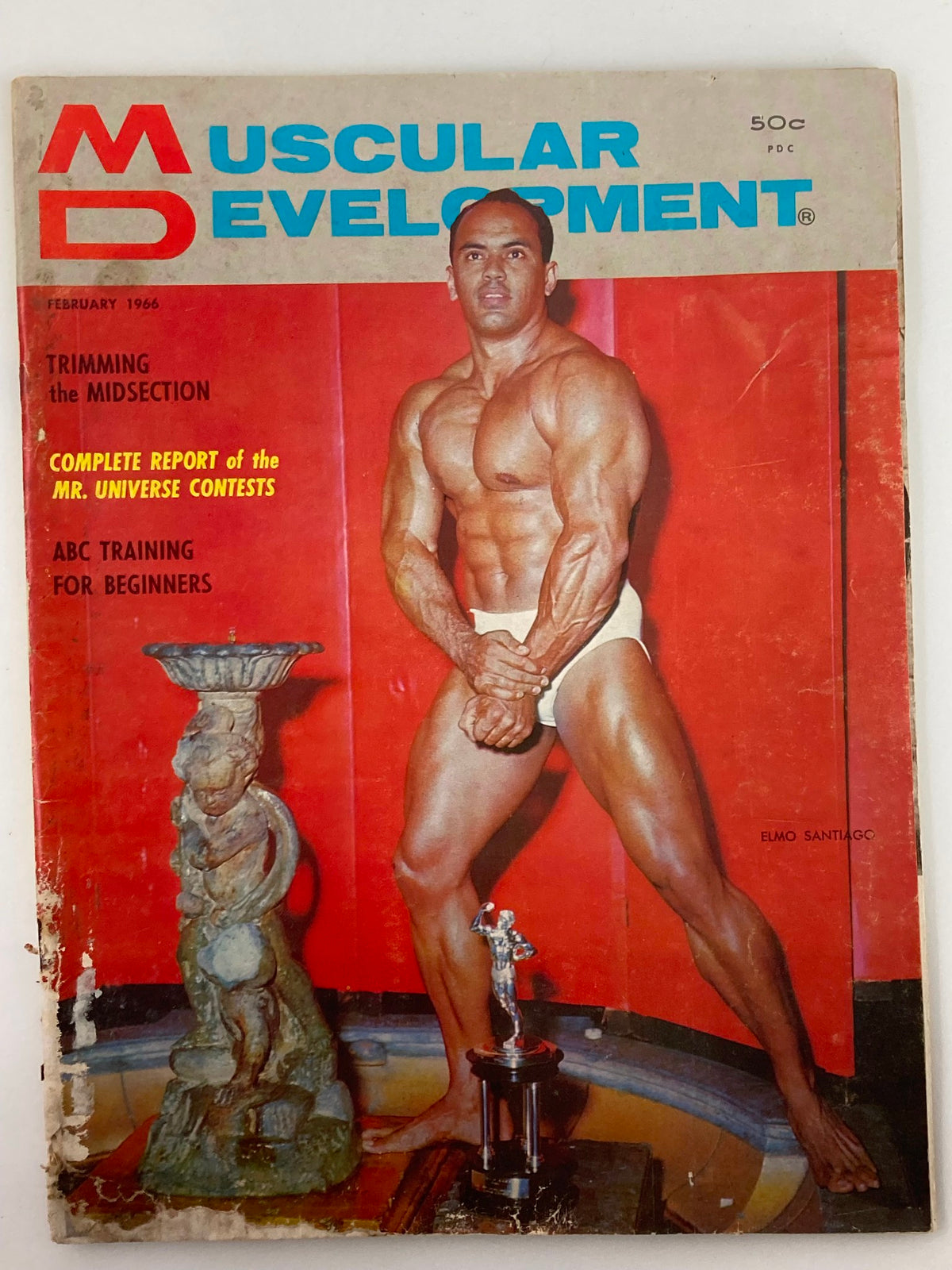 VTG Muscular Development Magazine February 1966 Vol 3 #2 featuring bodybuilder Elmo Santiago on the cover, showcasing his muscular physique against a vibrant red backdrop.