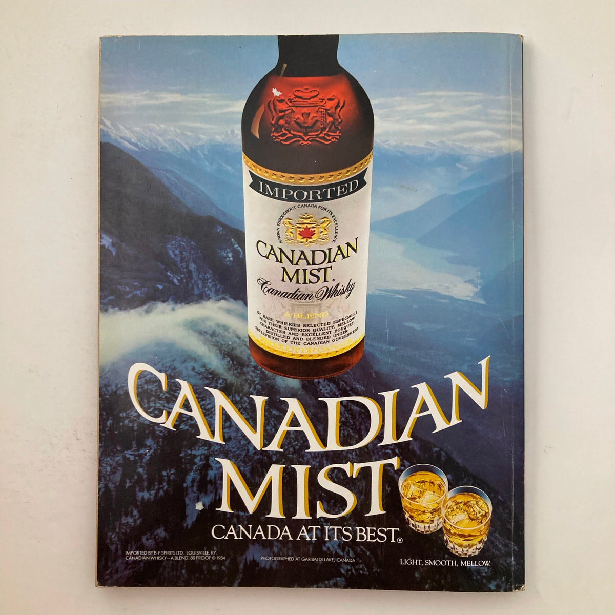 Back cover of VTG Playboy Magazine March 1987 advertising Canadian Mist whisky, presenting a scenic background.