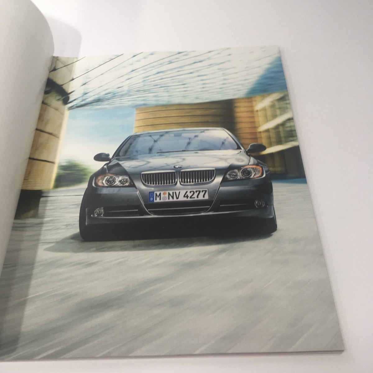Inside view of the 2008 BMW 3 Series Sedan 335i 335xi Dealership Car Auto Brochure Catalog showing a dynamic image of a black BMW car driving in a modern architectural setting.