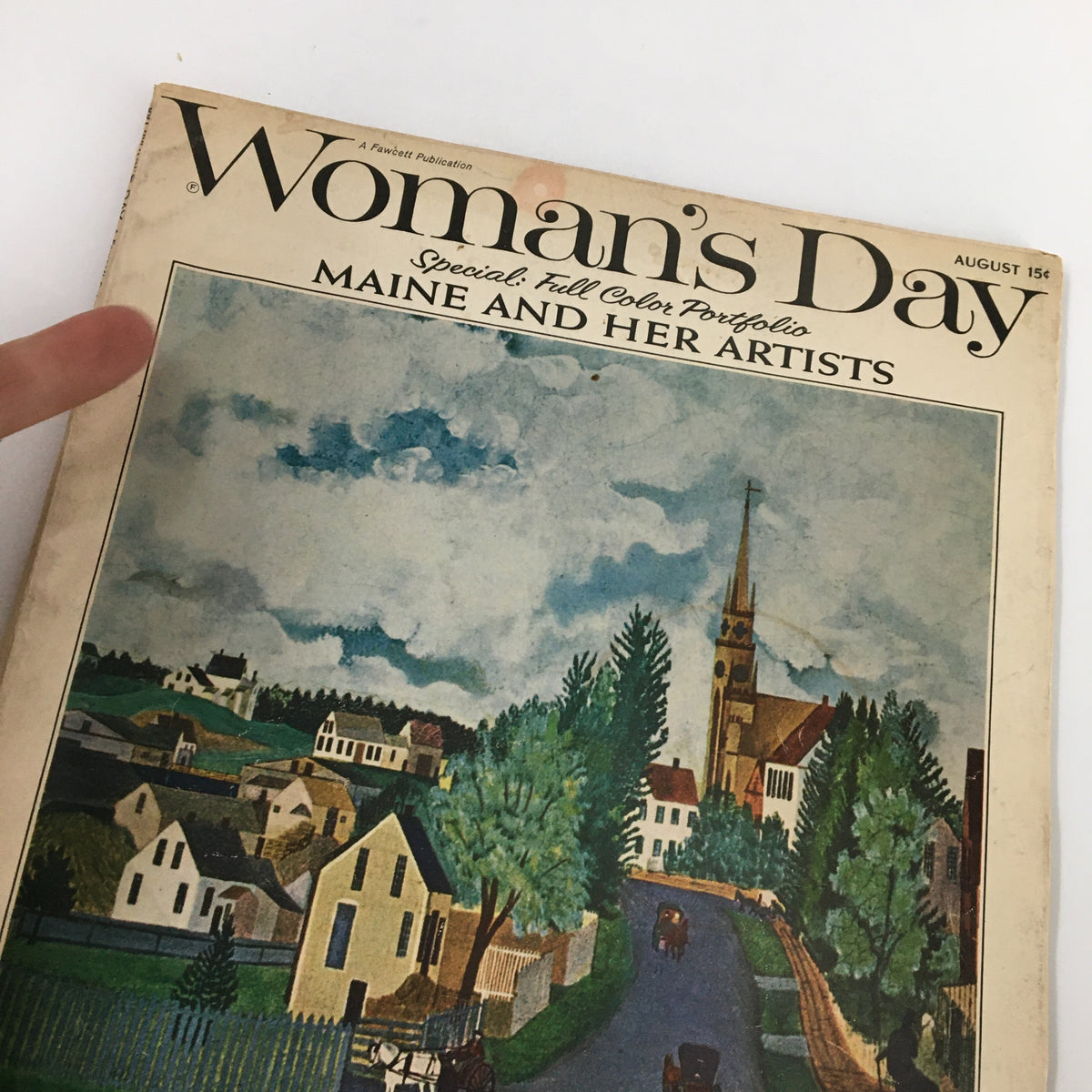 Close-up view of the cover of VTG Woman's Day Magazine August 1964 titled 'A Lovely Conspiracy', showcasing the artistic details of a Maine landscape with a finger pointing at the magazine's title.