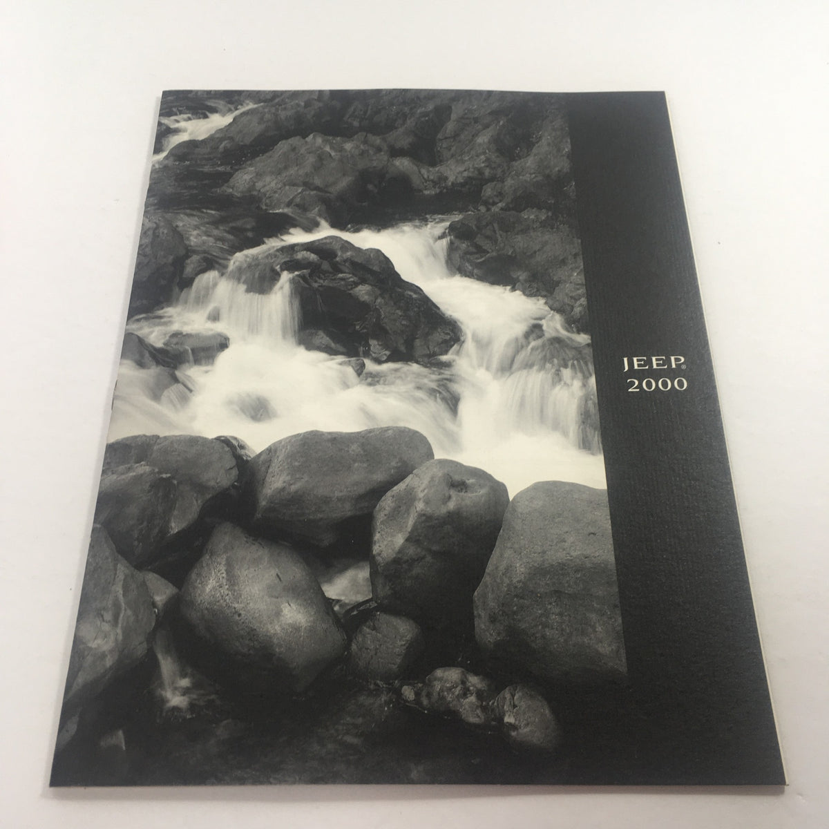 Cover of the 2000 Jeep Cherokee, Grand Cherokee Wrangler Dealership Car Auto Brochure Catalog featuring a serene black and white image of flowing water and rocks.