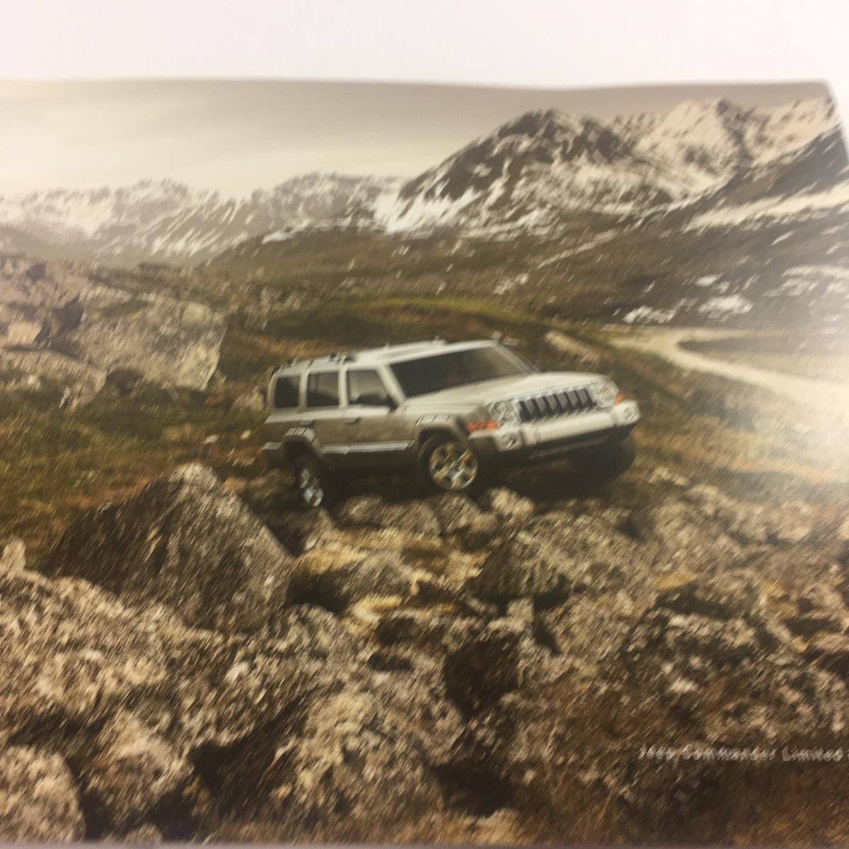 Image from the 2006 Jeep Commander Dealership Car Auto Brochure Catalog showing a silver Jeep Commander navigating rocky terrain, emphasizing its off-road capabilities.