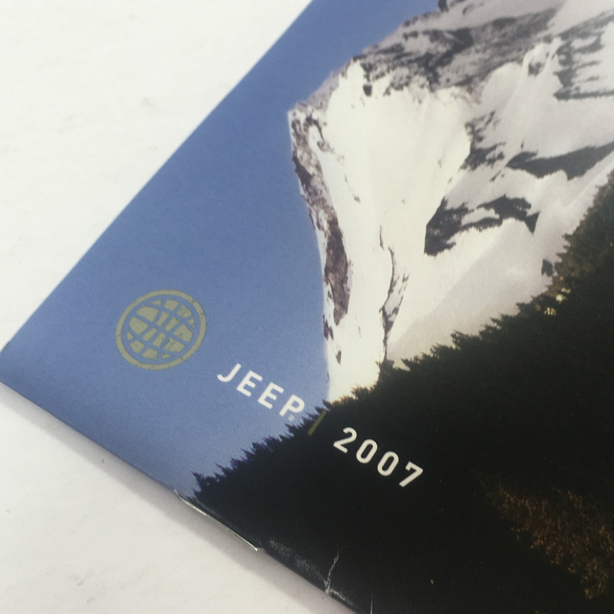 Close-up of the 2007 Jeep logo and emblem on the dealership car auto brochure catalog, highlighting the year and branding.