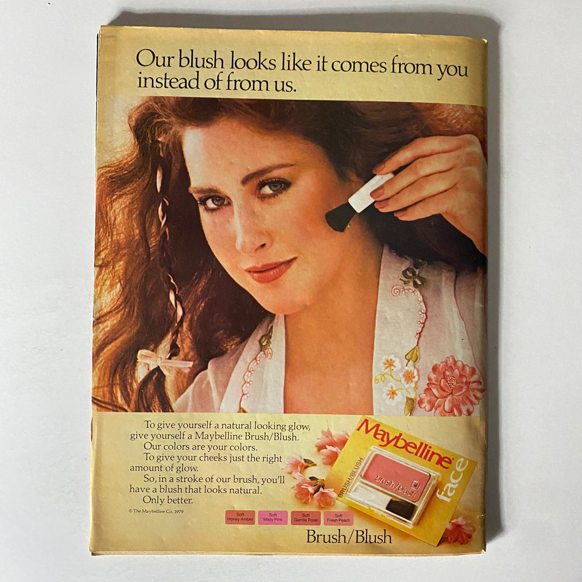 February 1980 - 16 Magazine advertisement for Maybelline featuring a model demonstrating blush application.