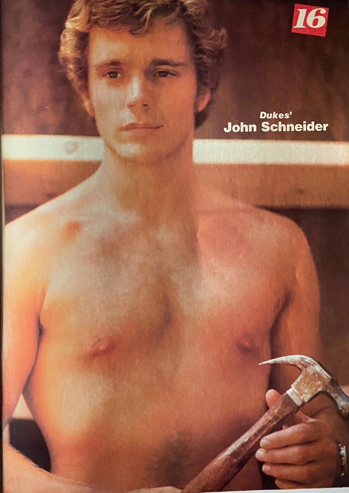 Image of John Schneider from 16 Magazine December 1981, portraying him shirtless with a hammer, emphasizing his charm and appeal.