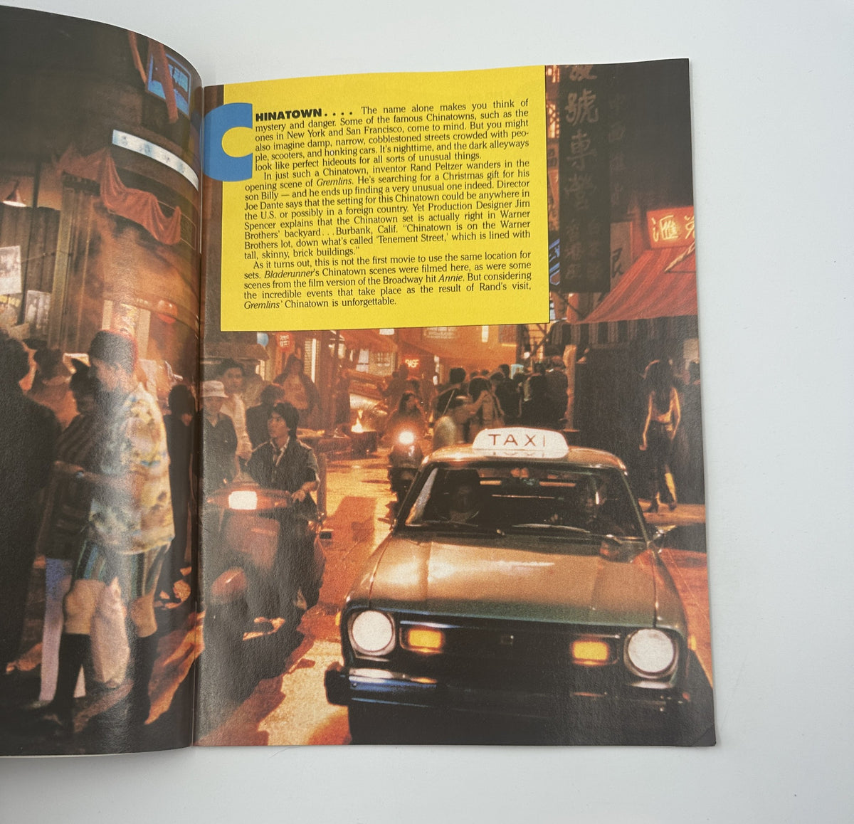 Interior image from the Gremlins Souvenir Magazine Official Collector’s Edition depicting a scene from 'Ninatown' with a taxi and characters, capturing the essence of the film's atmosphere.