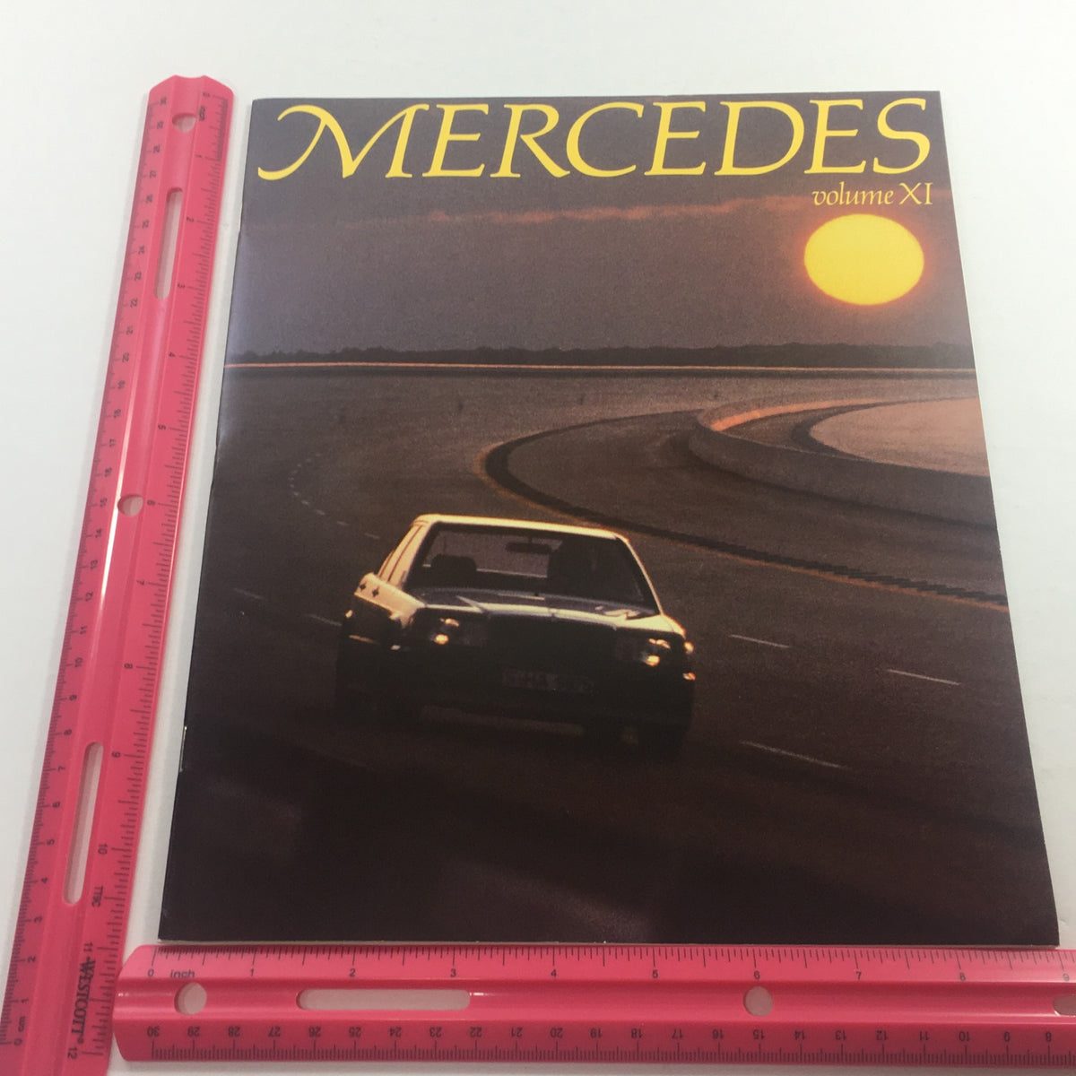 Front cover of the 1983 Mercedes Volume XI Dealership Car Auto Brochure Catalog featuring a sunset and a Mercedes car on a racetrack.