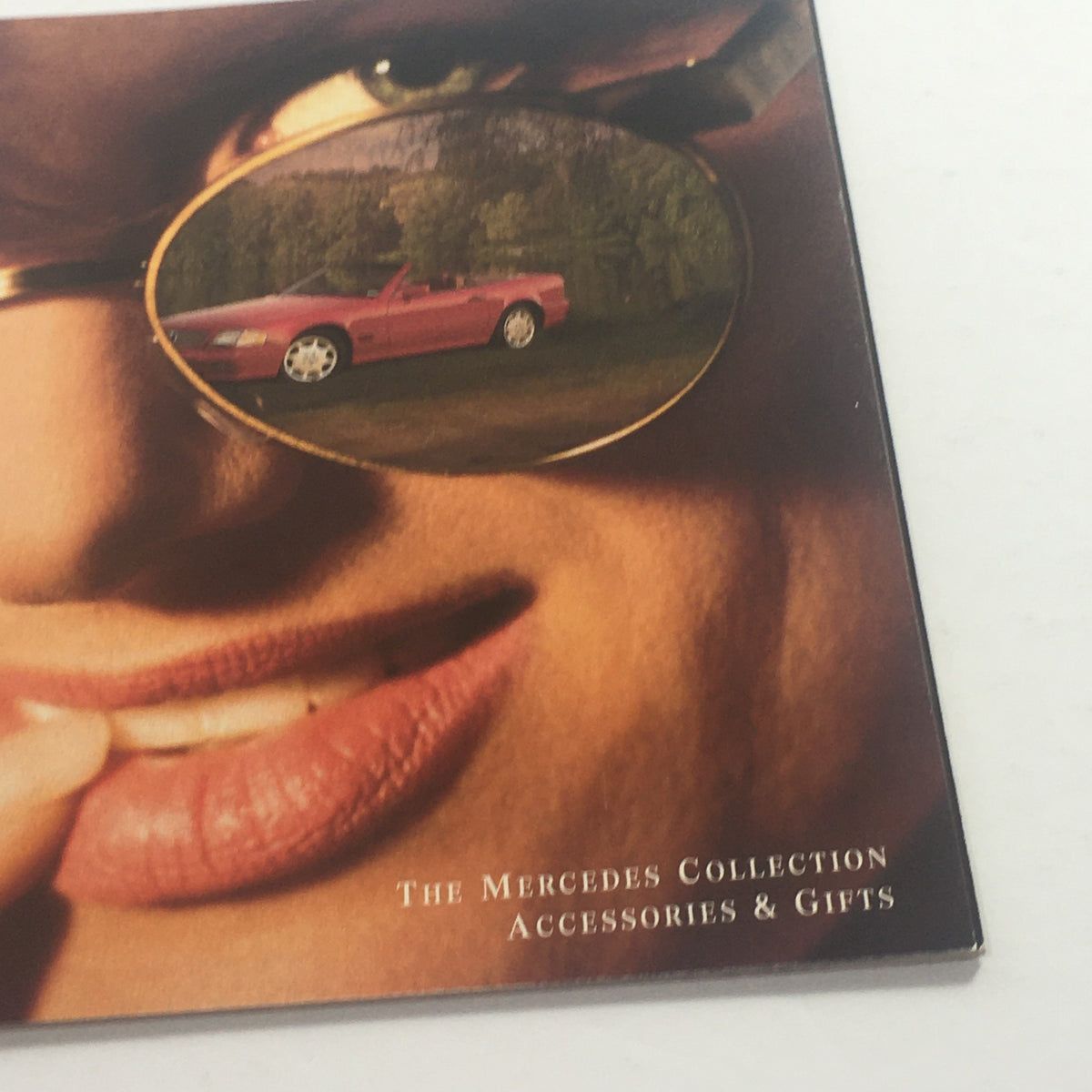 Close-up of the 1994 Mercedes-Benz Collection Accessories Dealership Car Auto Brochure Catalog cover showing a model's lips and sunglasses reflecting a red Mercedes-Benz car.