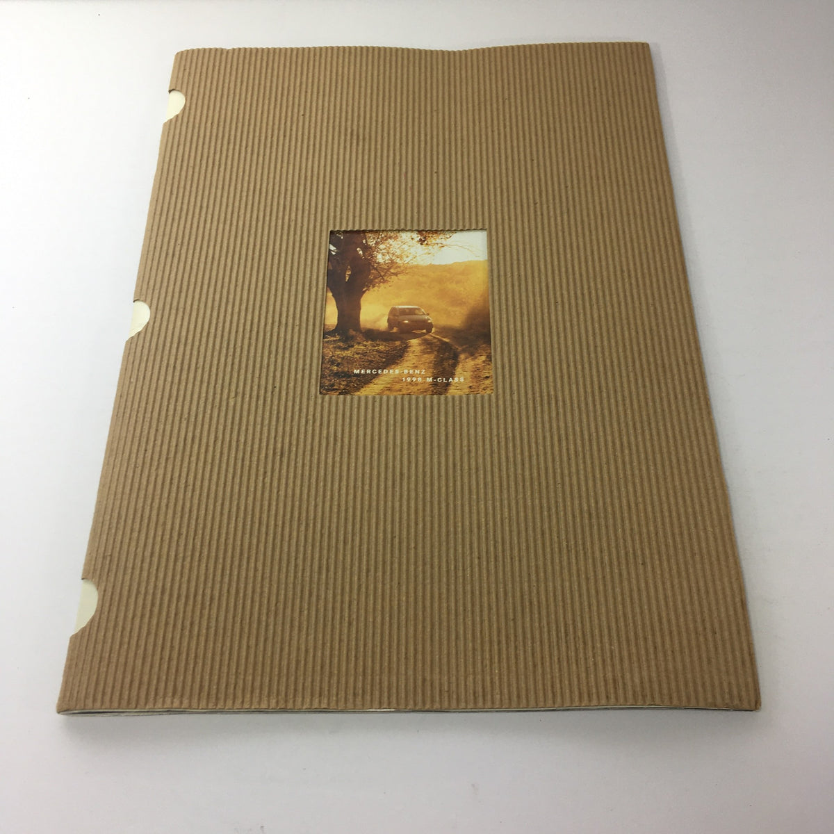 Cover of the 1998 Mercedes-Benz M-Class dealership car auto brochure catalog, featuring a scenic photo of a vehicle on a dirt road in a golden hour setting.