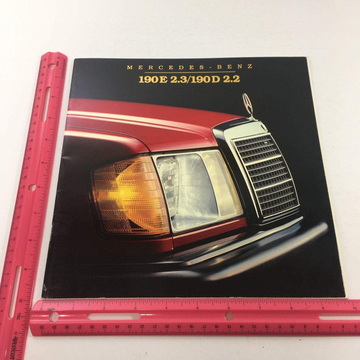 Front cover of the 1984 Mercedes-Benz 190E 2.3/190D 2.2 Dealership Car Auto Brochure featuring the iconic Mercedes-Benz logo and a car detail.