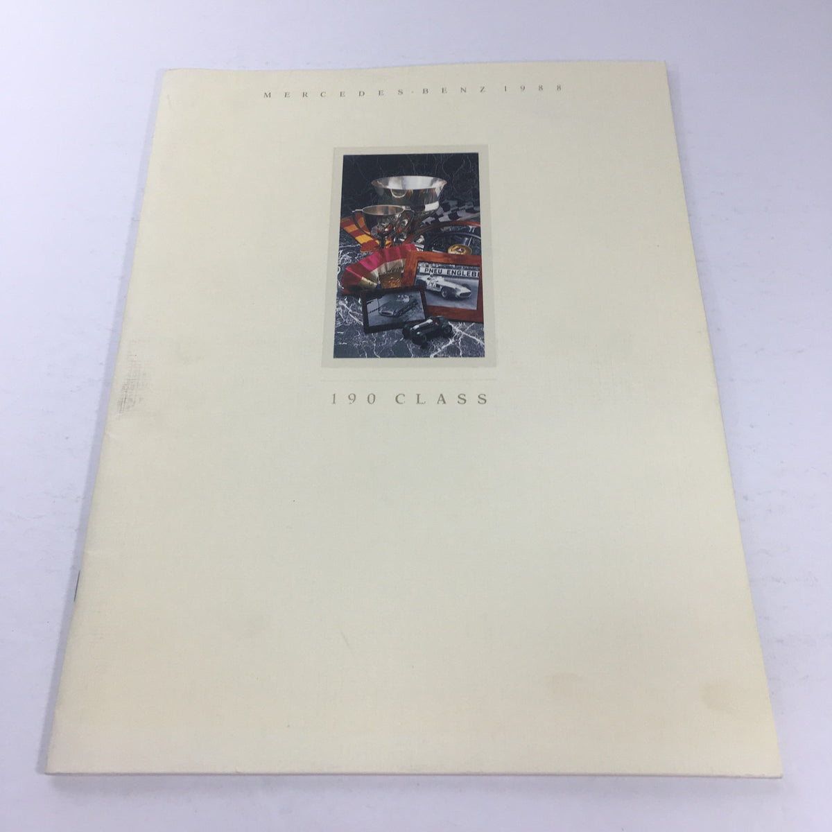Cover of the 1988 Mercedes-Benz 190-Class Sedan Dealership Car Auto Brochure Catalog showcasing elegant design and automotive memorabilia.