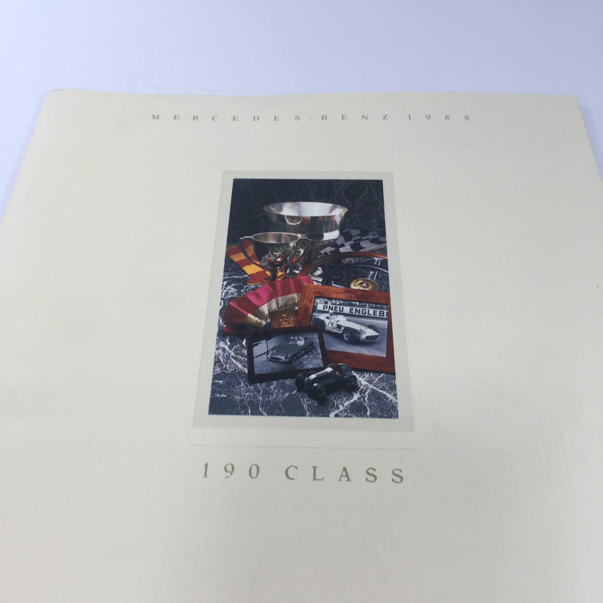 Detailed view of the cover of the 1988 Mercedes-Benz 190-Class Sedan Dealership Car Auto Brochure Catalog featuring iconic car-related items.