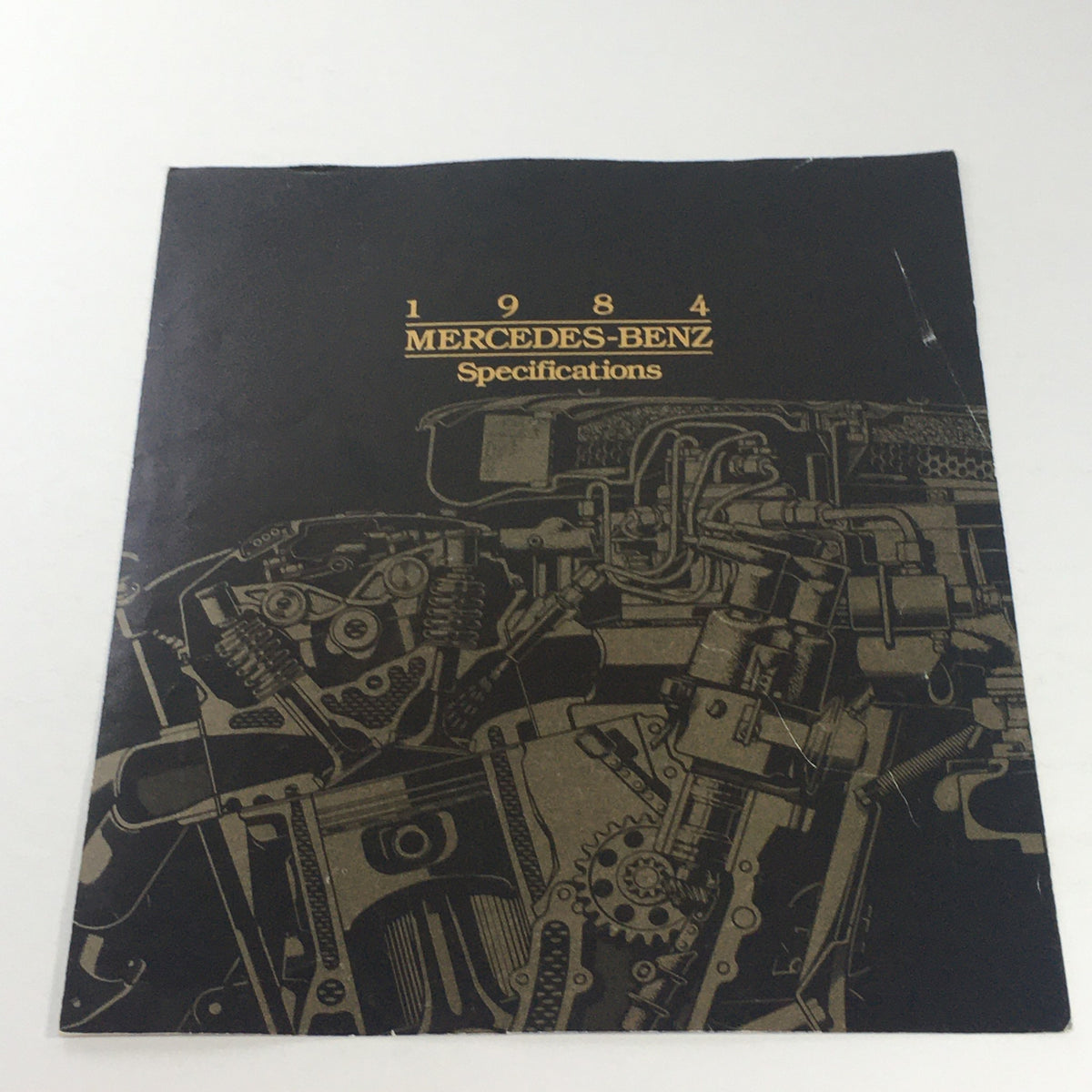 Cover of the 1984 Mercedes-Benz Specifications Features Dealership Car Auto Brochure Catalog showcasing intricate engine design.