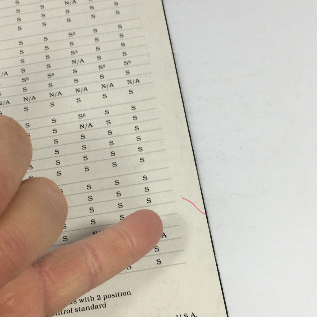 Close-up view of a page from the 1984 Mercedes-Benz specifications brochure featuring detailed information and specifications, highlighted by a finger showing various features.