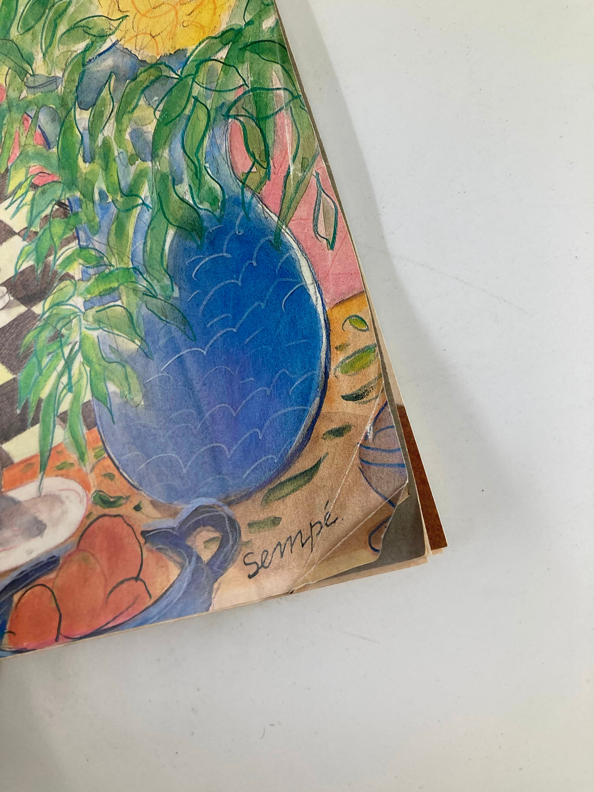 Detail of The New Yorker Magazine April 15 1985 cover, highlighting the signature of artist Jean-Jacques Sempe alongside a blue vase and still-life elements.