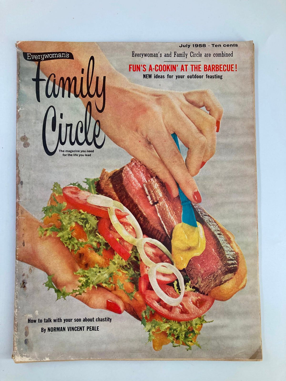Vintage Family Circle Magazine from July 1958 titled 'Fun's A-Cookin' at the Barbecue' showcasing a colorful cover with a hand holding a delicious BBQ sandwich topped with lettuce, tomato, onion, and mustard.