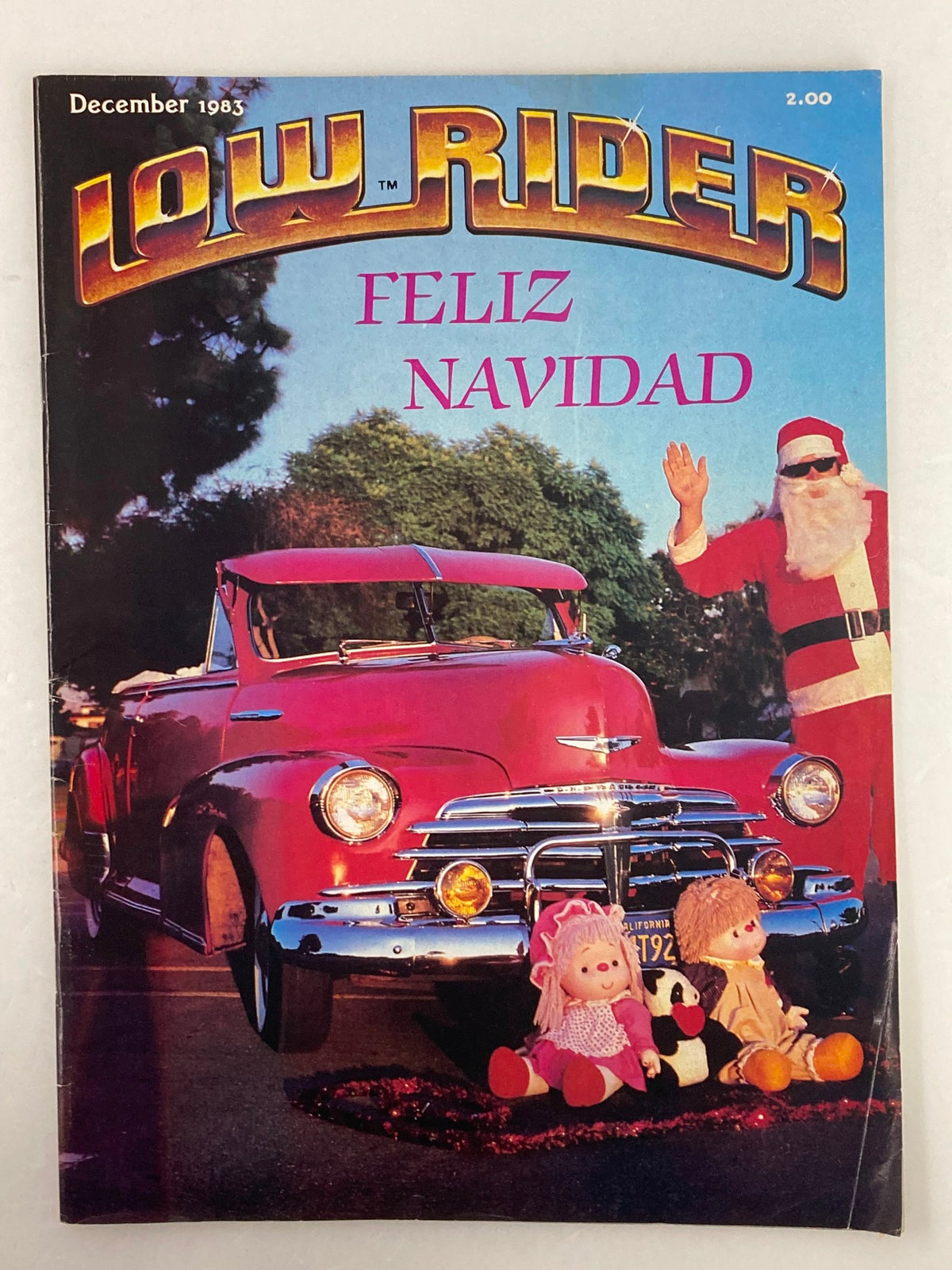 Cover of the December 1983 issue of Low Rider Magazine titled 'Feliz Navidad', featuring a festive lowrider car with Santa and holiday decorations.