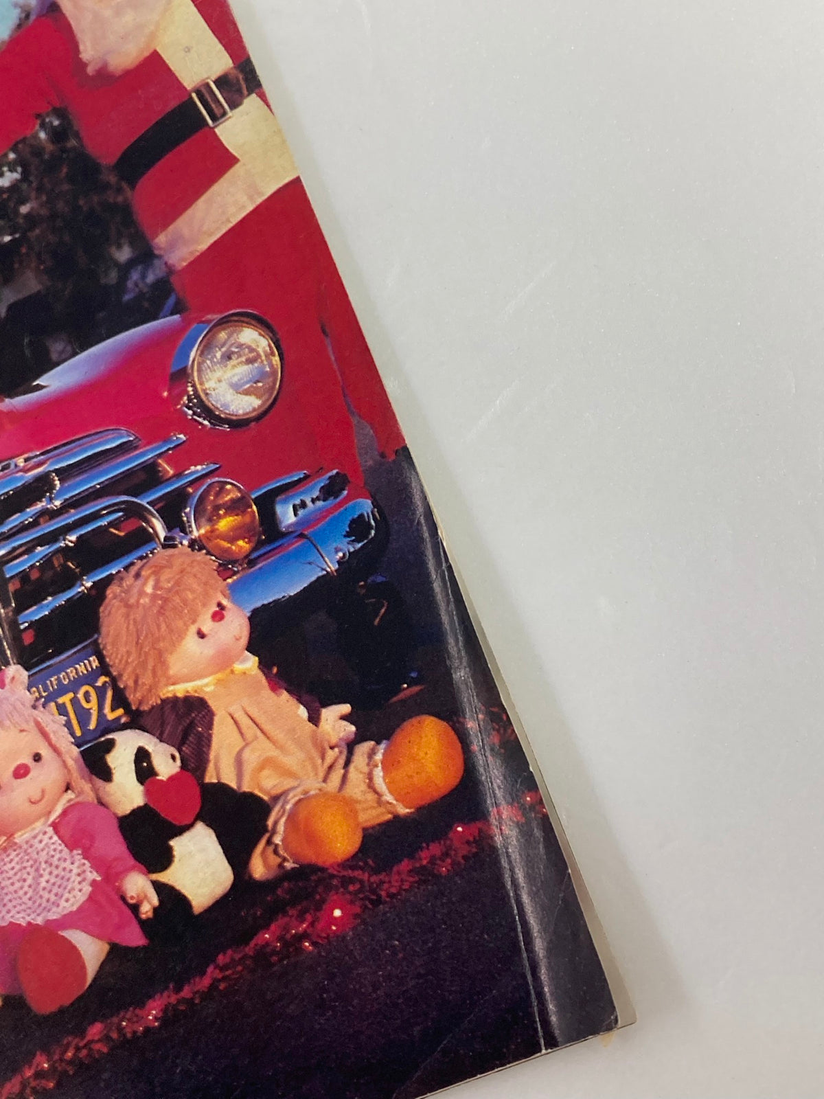 Close-up of the December 1983 Low Rider Magazine cover, showcasing details of the 'Feliz Navidad' theme with plush toys in front of a classic car.