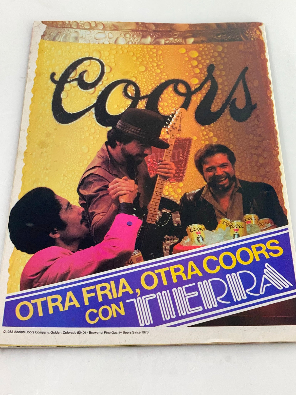 Promotional image from VTG LowRider Magazine December 1983 showcasing a Coors beer advertisement with musicians celebrating, complementing the festive spirit of the Santa's Sleigh Feliz Navidad issue.