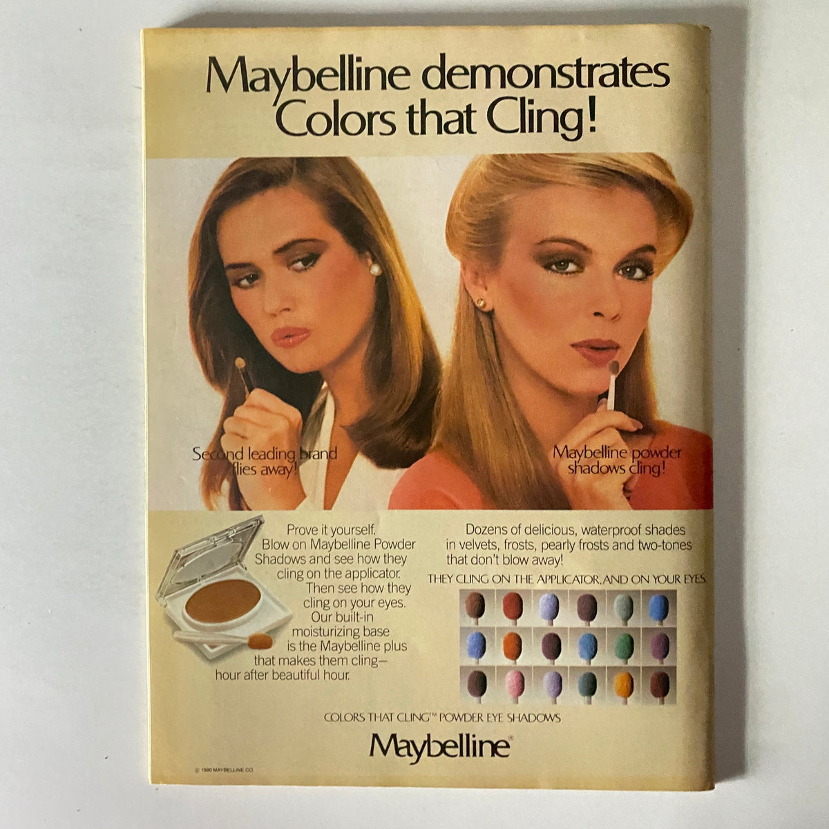 Vintage Maybelline advertisement demonstrating 'Colors that Cling'. The ad features two models showcasing makeup products and their application techniques.